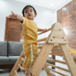 Ein kleiner Junge klettert auf einem Pikler Dreieck von Montessori.